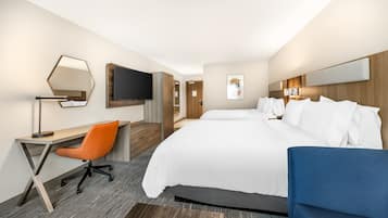 Une chambre d’hôtel comprenant un lit, un bureau avec une chaise, une télévision et un grand miroir.