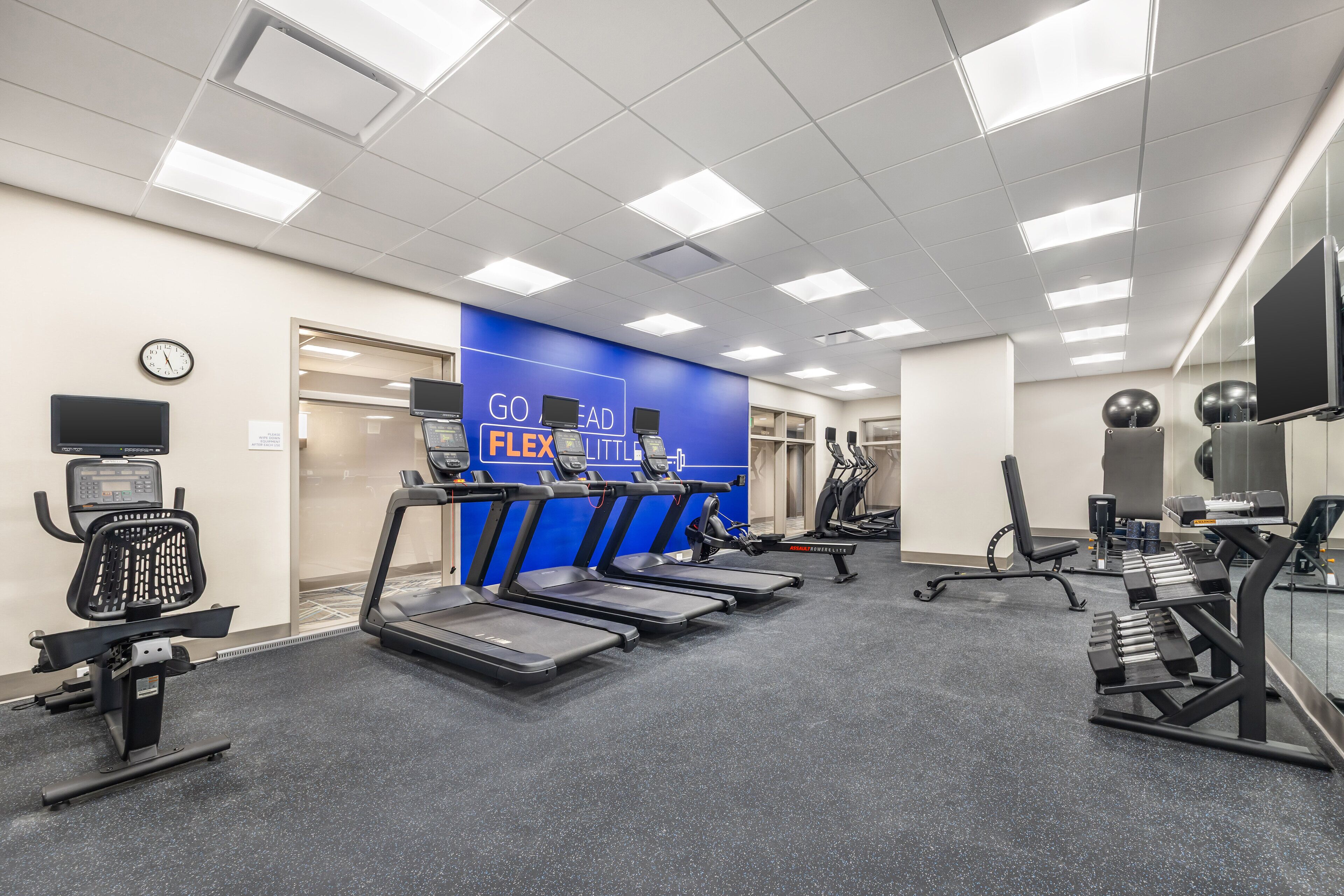 A gym with treadmills, a stationary bike, and a rowing machine.