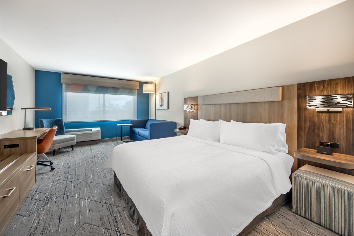 Una habitación de hotel con una cama grande, un escritorio, una silla y una ventana.