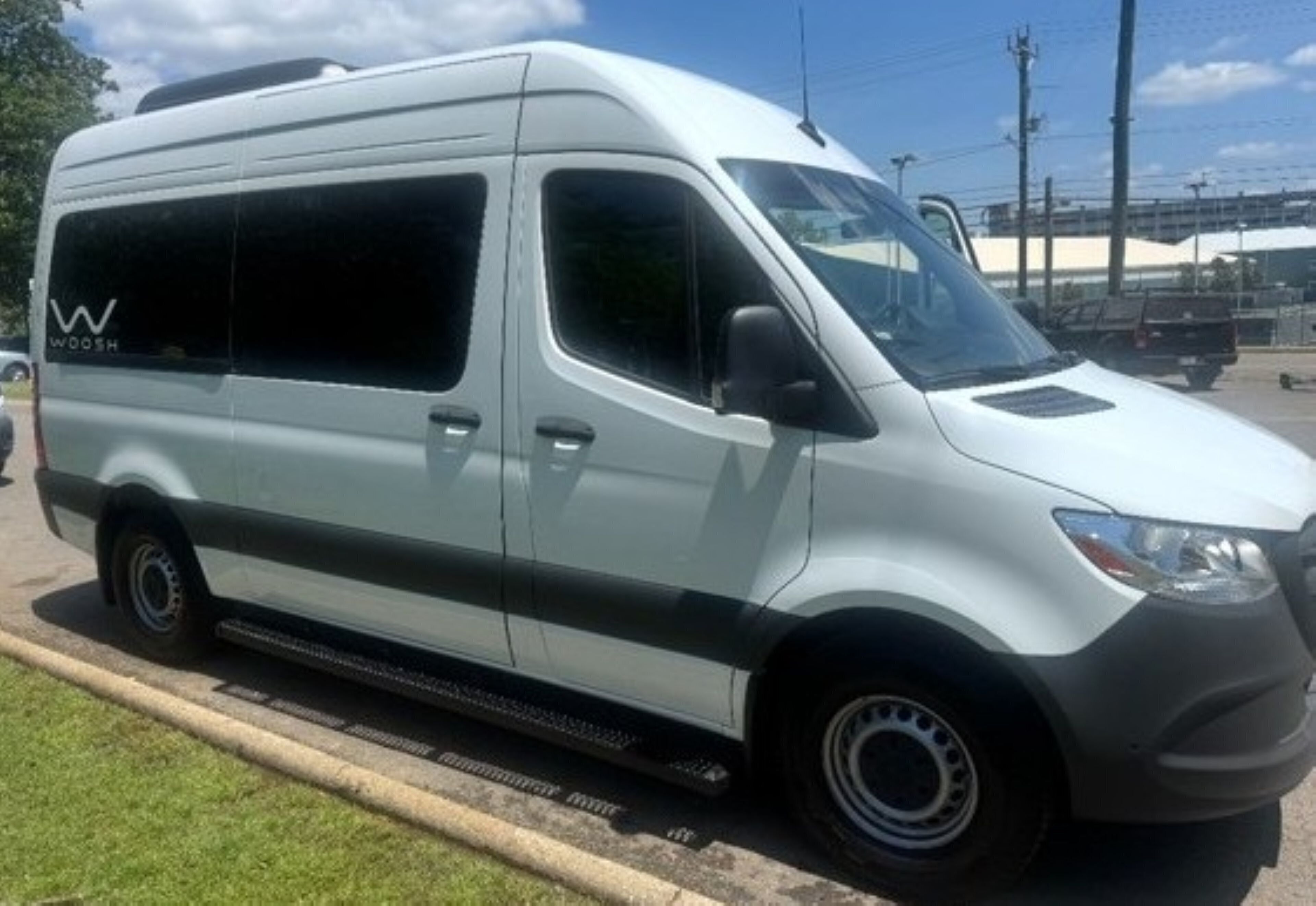 A white van parked on a paved area with a grassy verge.
