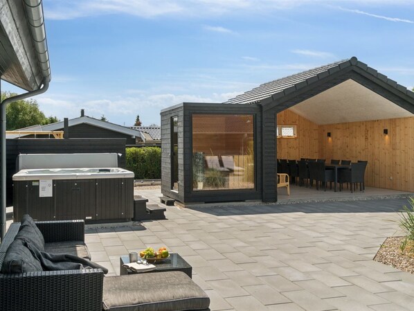 Une terrasse extérieure moderne dotée d’un jacuzzi, d’un espace salon et d’un coin repas en bois.