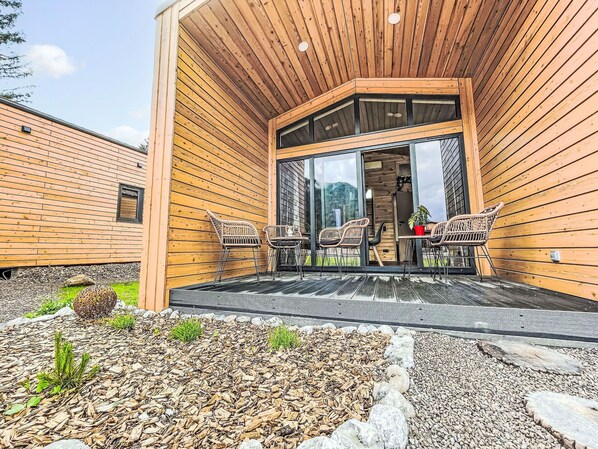 A wooden cabin with a covered patio, outdoor seating, and a view of the surrounding landscape. - Lovely apartment in villa for 5 people with A/C, TV and terrace (Fischbachau)
