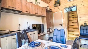 Interior de madera con comedor, cocina y una escalera.