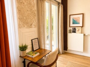 A room with a wooden table, a framed certificate, a potted plant, and a radiator. - Apartment with terrace and private garden near Disney & shopping center  (Bussy-Saint-Georges)