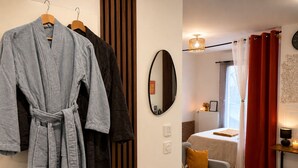 Ein Hotelzimmer mit Bett, Sofa, Tisch mit Lampe, Spiegel und Wanduhr.