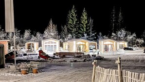 A row of cabins with large windows, a wooden fence, and snow-covered ground. - Cosy apartment in villa for 5 people with A/C, TV and terrace (Fischbachau)