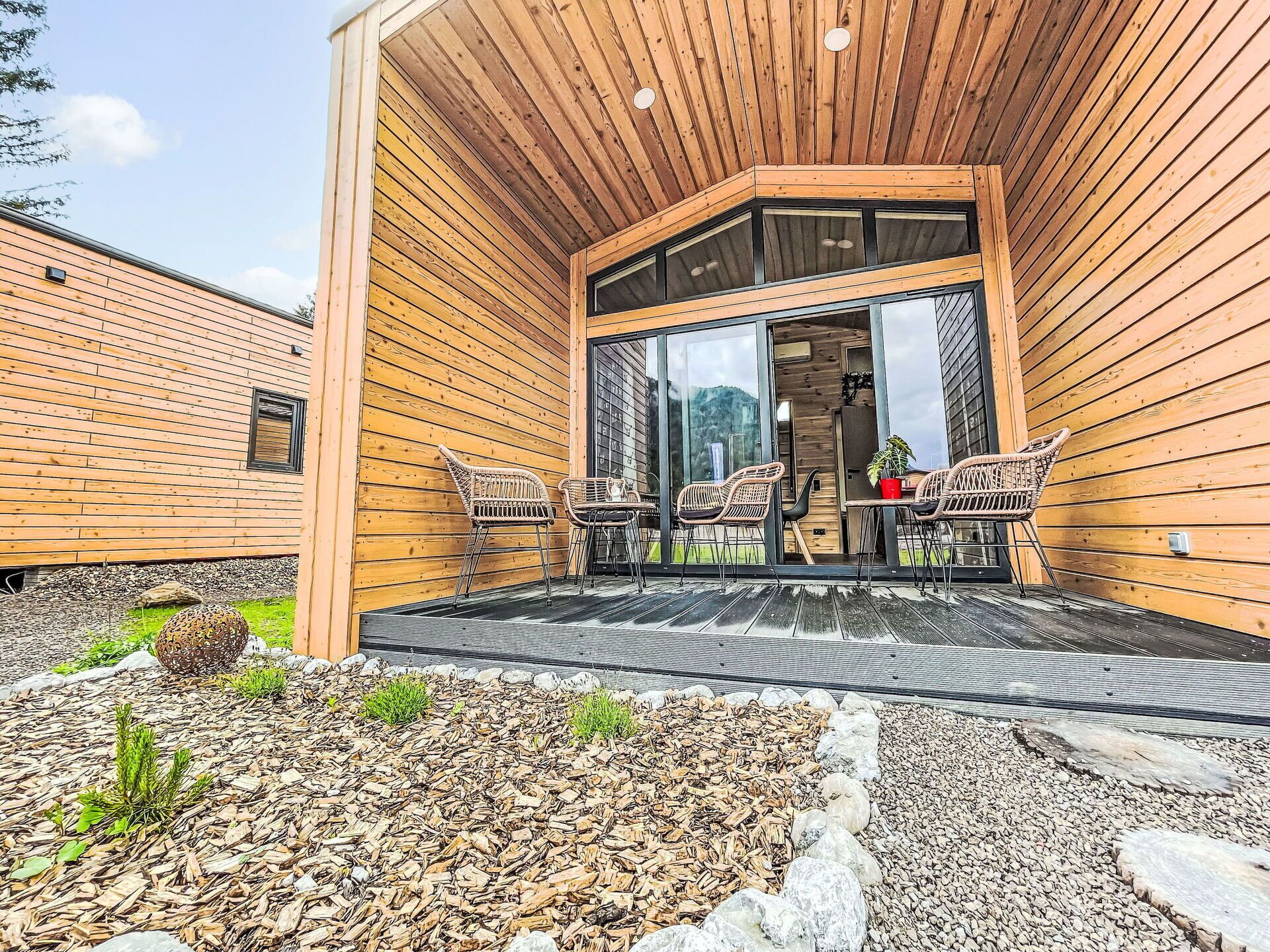Eine Holzdiele mit überdachter Terrasse, Sitzgelegenheiten im Freien und Blick auf die umliegende Landschaft.