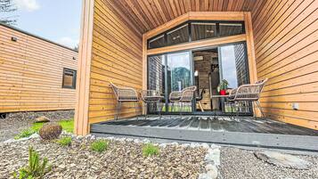 Eine Holzdiele mit überdachter Terrasse, Sitzgelegenheiten im Freien und Blick auf die umliegende Landschaft.