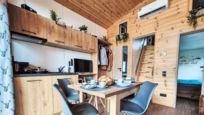 Eine kompakte Küche mit modernen Geräten, ein Essbereich mit zwei Stühlen und eine Holztreppe, die in einen anderen Raum führt.