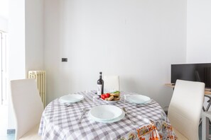 Un coin repas avec une nappe à carreaux, des assiettes blanches, une bouteille de vin et une assiette de nourriture.