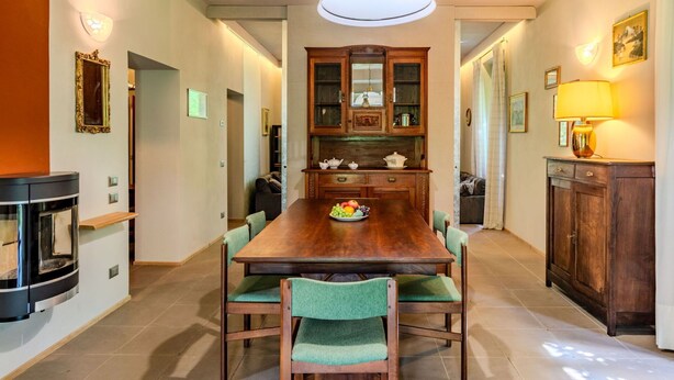 A dining area with a wooden table, green upholstered chairs, and a chandelier. - Stunning private villa for 8 people with private pool, WIFI, TV, terrace and panoramic view (Dervio)