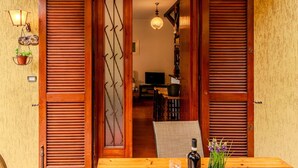 A wooden door with a metal gate, a table with a bottle and glass, and a potted plant. - Lovely apartment for 4 people with WIFI, A/C, TV, patio and pets allowed (Bellano)