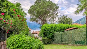 A garden with a variety of plants, a wooden fence, and a stone pathway. - Lovely apartment for 4 people with WIFI, A/C, TV, patio and pets allowed (Bellano)