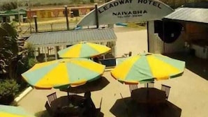 Ein Hotel Eingang mit einem Schild, auf dem 'Leadway Hotel Naivasha' steht, und Außenbereich mit Sonnenschirmen.