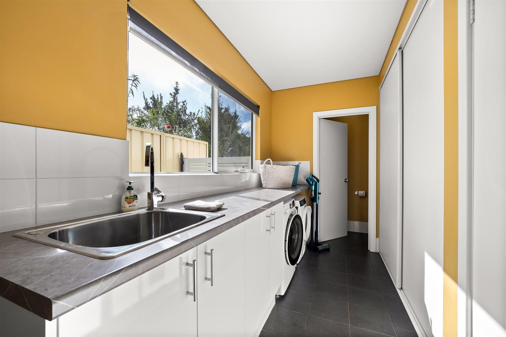 A modern kitchen with a large window, a washing machine, and a sink.