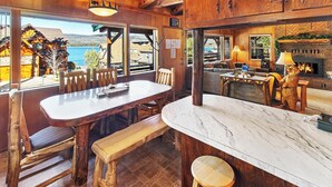 A wooden interior with a dining area, a fireplace, and a view of the outside.