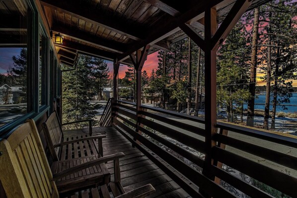 A wooden deck with benches overlooking a waterfront and forested area.