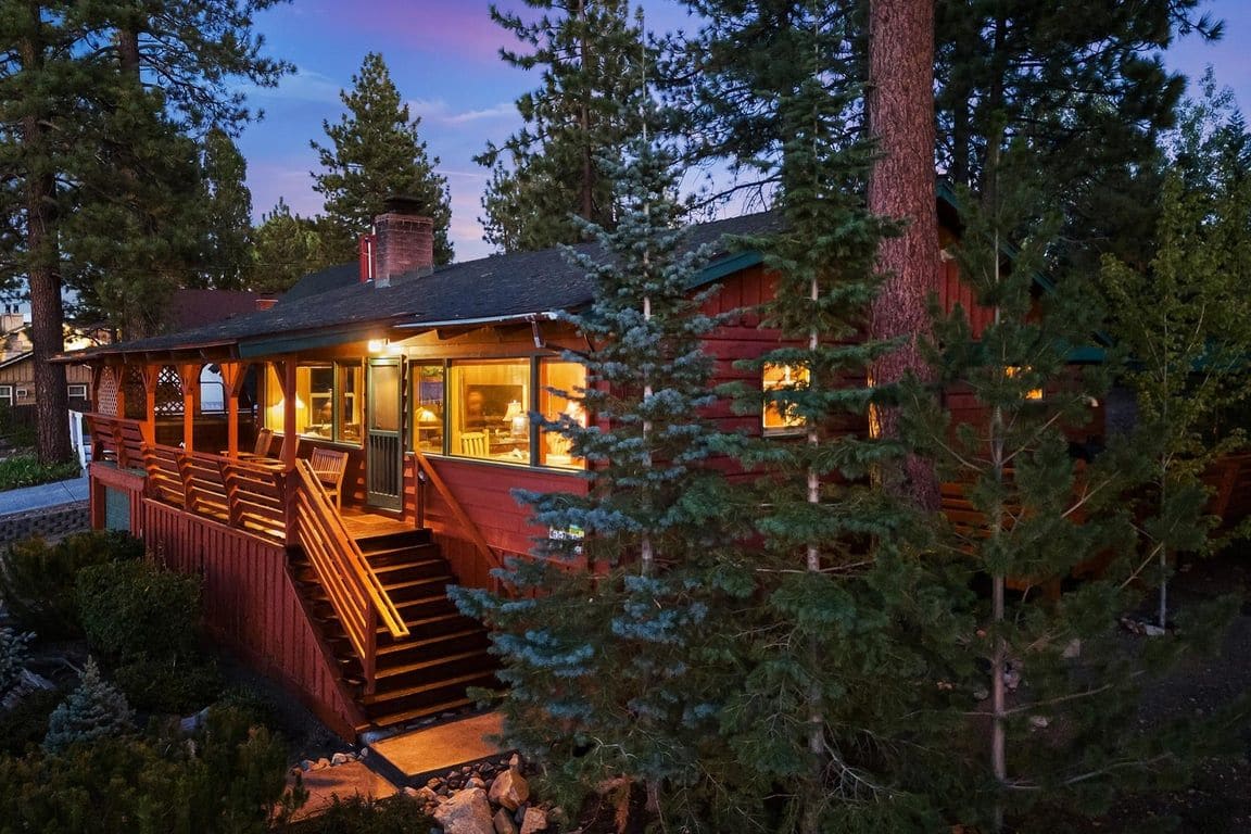 A cabin with a wooden exterior, a staircase leading to the entrance, and a surrounding forest.