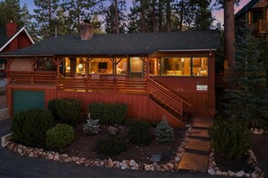 Een houten chalet met een veranda, een trap en een verzorgde tuin.