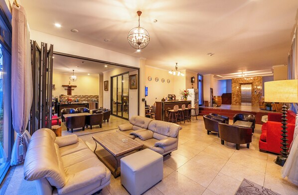 A spacious living area with a sofa set, a coffee table, and a dining area with chairs and a bar. - Guava Hill Boutique Hotel (Lam Vien - Da Lat)