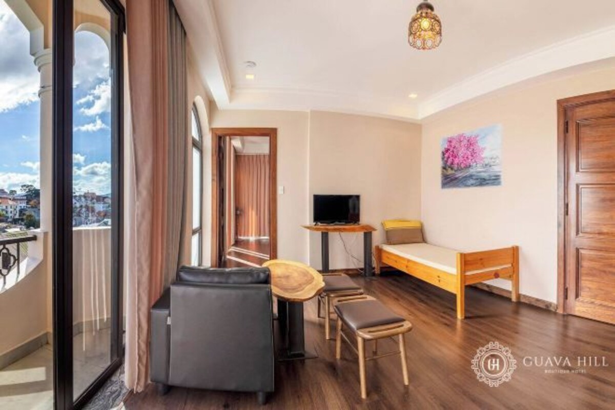A hotel room with a balcony, a bed, a TV, and a painting.