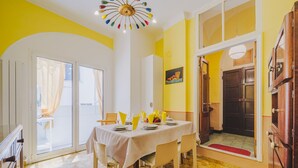 A dining area with a table set for four, a chandelier, and a yellow and white color scheme. - Lovely apartment for 6 people with WIFI and TV (Sestri Levante)