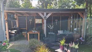 A covered patio with a grill, seating area, and potted plants. - Private Sanctuary/Zen Den/nature lovers (Voorthuizen)