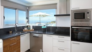 Une cuisine moderne équipée d’un lave-vaisselle, d’un four et d’une grande fenêtre avec un parasol.