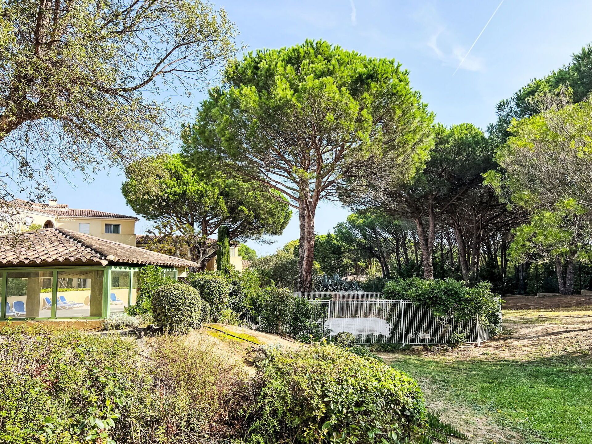Une villa dotée d’un toit en tuiles, entourée d’une végétation luxuriante et d’arbres.
