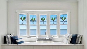 A bay window with five panes, a white interior, and a view of the sea.