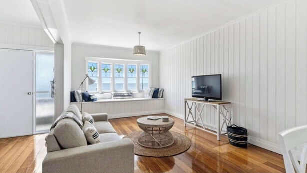 A modern living room with a sofa, a round coffee table, a TV on a stand, and a window with a view.