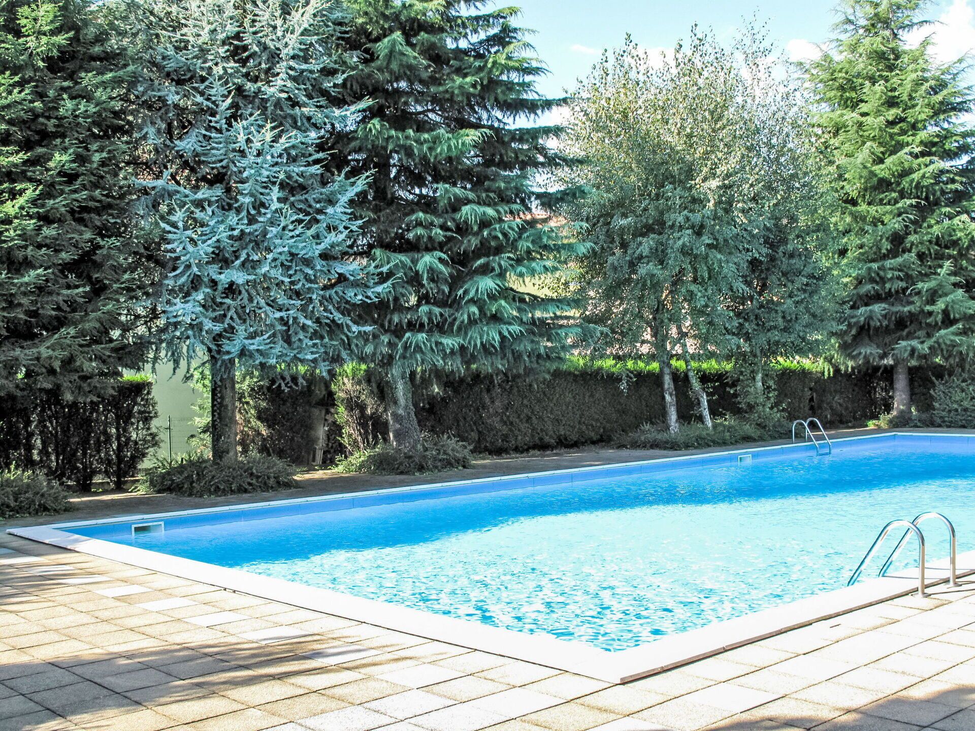 A rectangular swimming pool with a clear blue water surface, surrounded by a tiled deck.