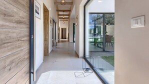 A modern hallway with wooden paneling, a glass door leading to a patio, and a hanging light fixture.