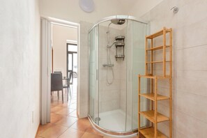 A glass-enclosed shower with a wooden shelf, a tiled floor, and a door leading to a dining area. - 4125 Casa di Casanello by Barbarhouse (Lecce)