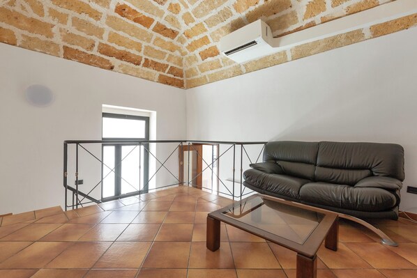 A spacious living area with a leather sofa, a glass coffee table, and a view through a glass door to a balcony. - 4125 Casa di Casanello by Barbarhouse (Lecce)