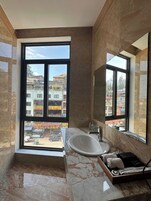 A modern bathroom with a large window, a marble sink, and a wooden vanity.