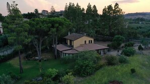 Une maison de plain-pied, dotée d’un toit en tuiles, entourée d’une pelouse bien entretenue et d’arbres.