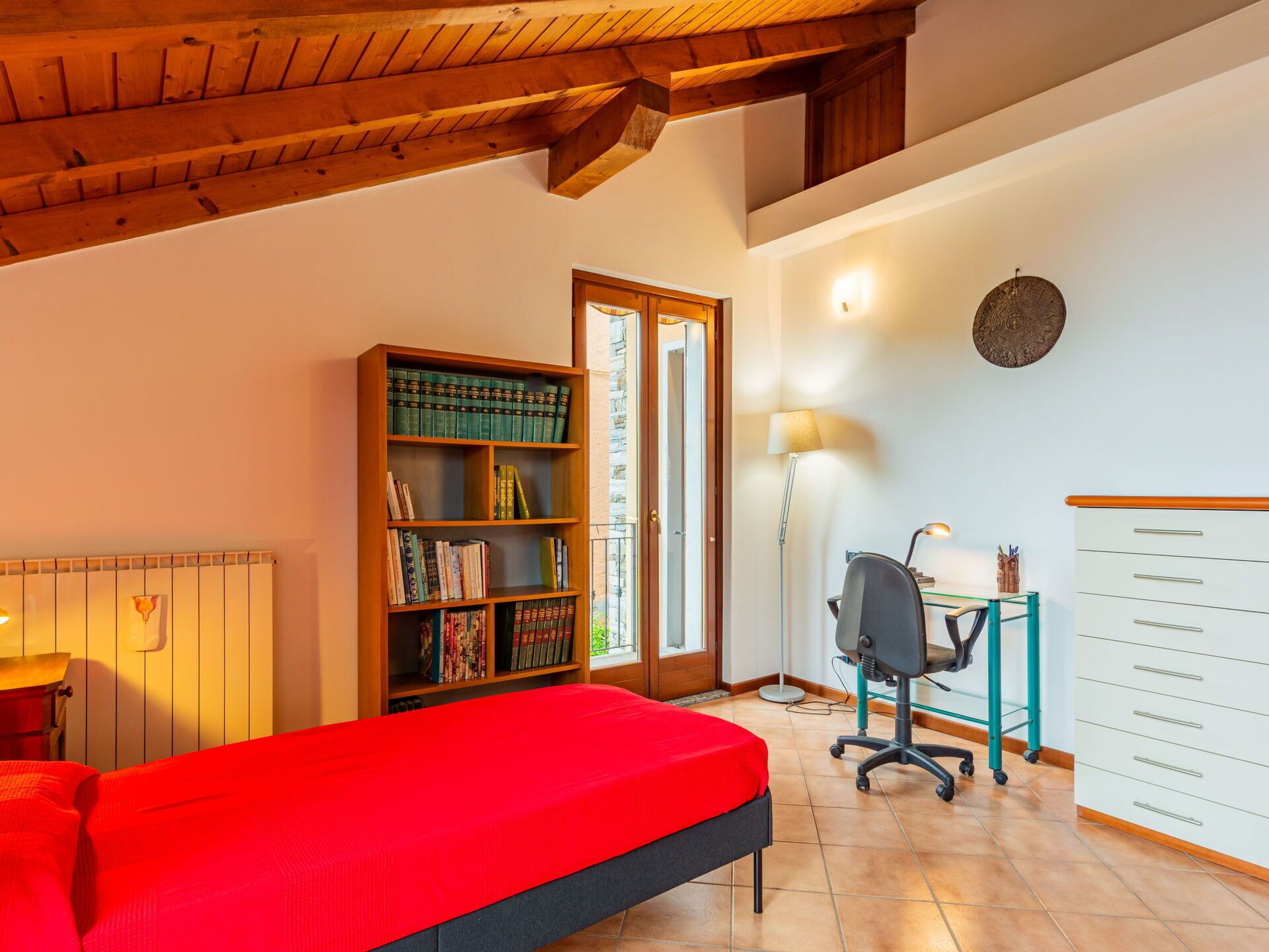 Une pièce comprenant un lit, une bibliothèque, un bureau avec une chaise et une armoire blanche.