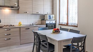 Eine moderne Küche mit Holzausbau, einem Gasherd und einem Essbereich mit Tisch und Stühlen.
