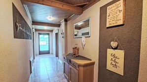 A hallway with a wooden ceiling, a mirror, a small cabinet, and a door leading to a bright room. - Stunning  villa for 8 guests with WIFI, TV, balcony and pets allowed (Ramsau Im Zillertal)
