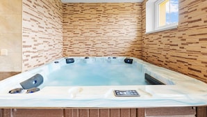 Ein Whirlpool mit Bedienfeld, umgeben von Holzverkleidungen und einem Fenster.