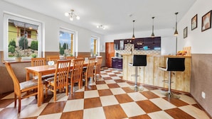 Eine geräumige Küche mit Schachbrettmuster-Boden, Holztisch und Barhocker.