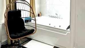 A room with a hanging chair, a bathtub, and a patterned floor. - La Suite Private Spa Blue in the heart of Douai (Douai)