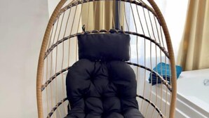 A hanging chair with a black cushion in a room with patterned carpet and a white piece of furniture in the background. - La Suite Private Spa Blue in the heart of Douai (Douai)