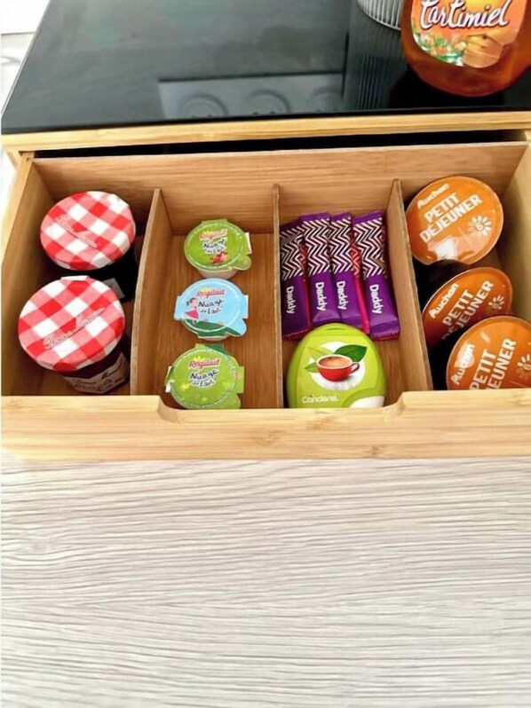 A wooden drawer with various food items including jars, candies, and a bottle.