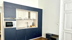 A modern kitchen with dark cabinetry, a built-in microwave, and a sink. - La Suite Private Spa Blue in the heart of Douai (Douai)