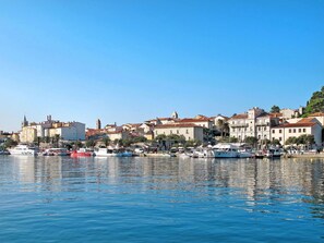 A coastal town with historic buildings, a marina with boats, and a clear blue sky.