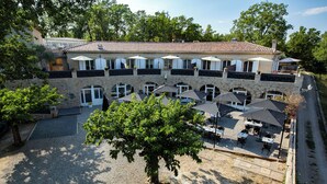 A courtyard with outdoor seating, a large tree, and a building with multiple windows and balconies. - RANDOM LISTING (Sainte-Tulle)
