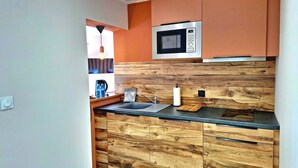 A modern kitchen with wooden cabinetry, a built-in microwave, and a countertop with a sink. - RANDOM LISTING (Sainte-Tulle)