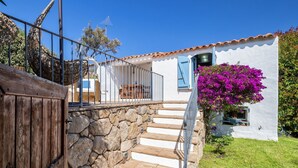 Um edifício branco com uma escadaria de pedra que leva a um deck de madeira.